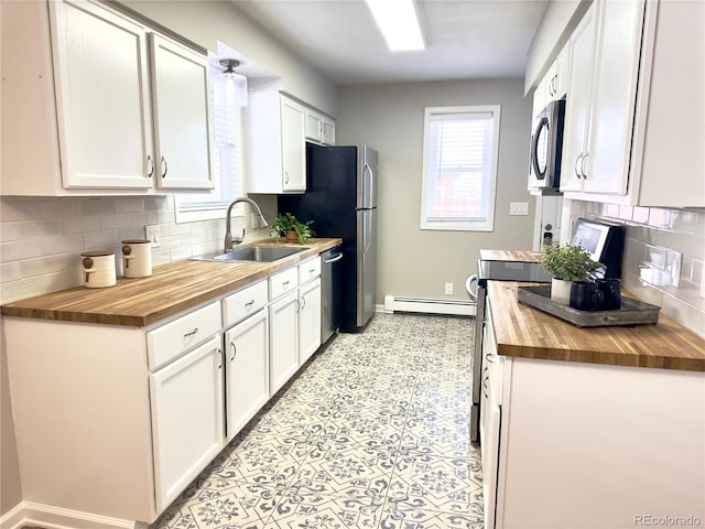 kitchen with butcher block countertops, decorative backsplash, sink, stainless steel appliances, and white cabinets