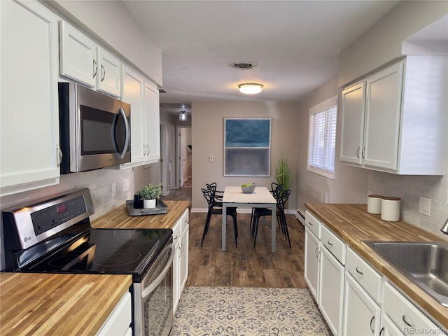 kitchen with butcher block counters, stainless steel appliances, and white cabinetry