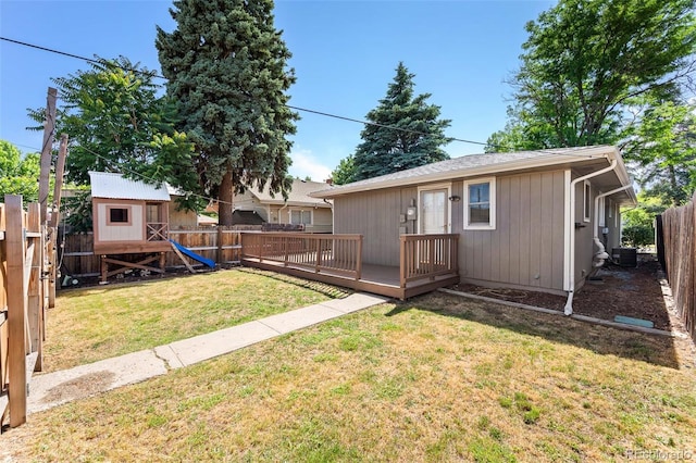 back of house featuring central AC unit, a deck, a storage unit, and a lawn