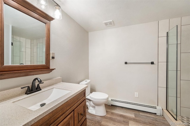 bathroom with toilet, hardwood / wood-style flooring, a shower with door, a baseboard heating unit, and vanity