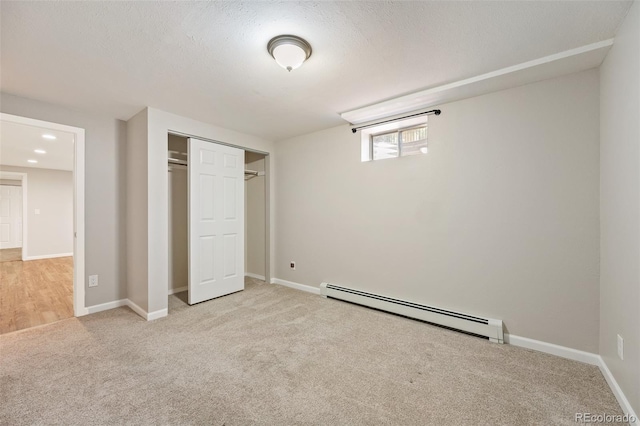 unfurnished bedroom with baseboard heating, a textured ceiling, a closet, and light carpet