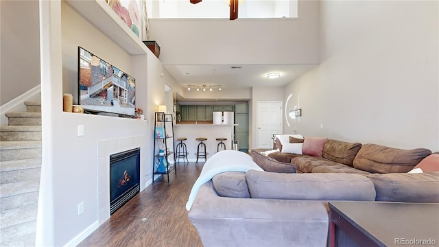 living room featuring a towering ceiling, dark hardwood / wood-style floors, and track lighting