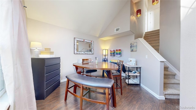 dining space featuring dark wood-type flooring and high vaulted ceiling