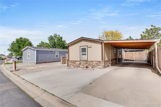 8426 Cook Way, Denver, CO 80229 - manufactured / mobile home with stone siding, concrete driveway, a carport, and stucco siding
