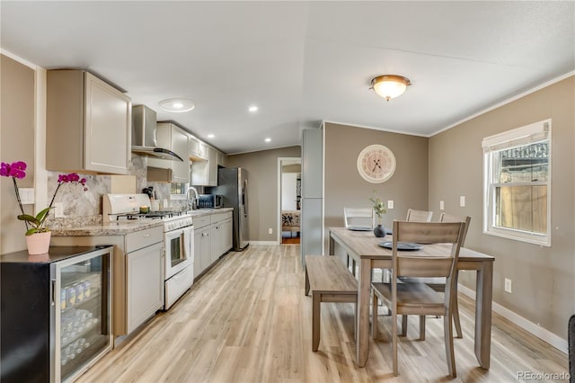 8426 Cook Way, Denver, CO 80229 - kitchen featuring wall chimney exhaust hood, wine cooler, gas range gas stove, freestanding refrigerator, and light wood-type flooring