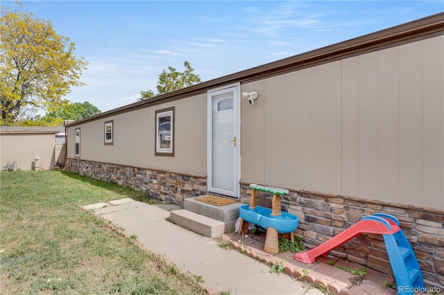 8426 Cook Way, Denver, CO 80229 - property entrance with stone siding, a yard, and a surveillance system