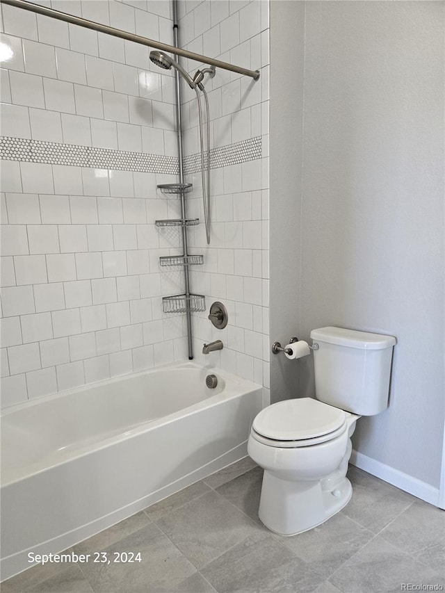 bathroom featuring tiled shower / bath, toilet, and tile patterned floors