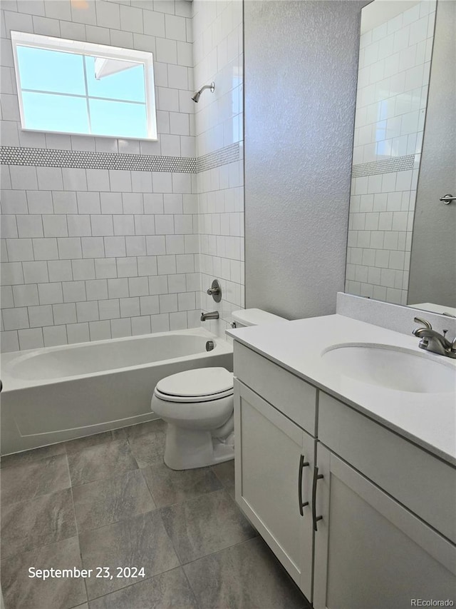 full bathroom with tile patterned flooring, tiled shower / bath combo, vanity, and toilet