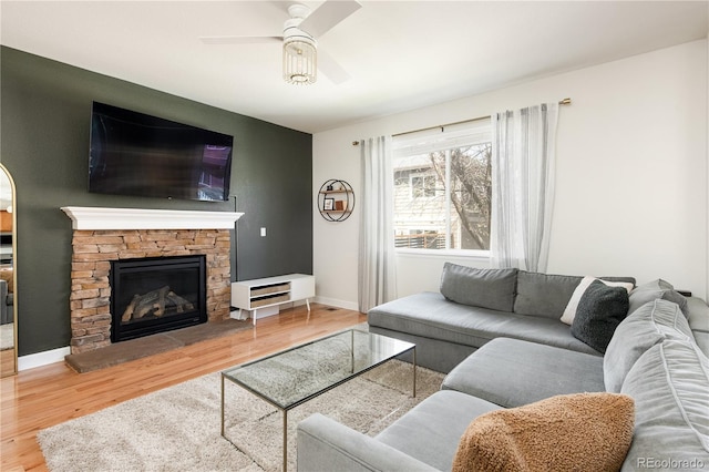 living room featuring baseboards, ceiling fan, wood finished floors, and a fireplace