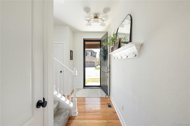 doorway featuring light wood-type flooring, baseboards, visible vents, and stairway