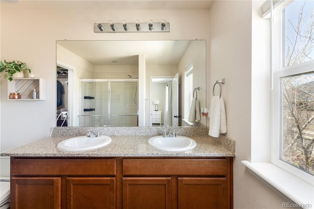 bathroom with double vanity, a sink, and a stall shower