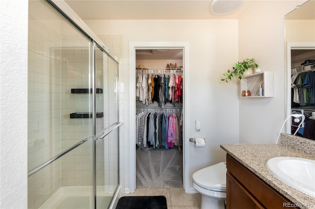 bathroom featuring vanity, toilet, tile patterned floors, a spacious closet, and a stall shower