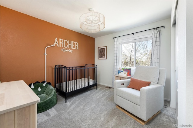 carpeted bedroom featuring baseboards and a crib