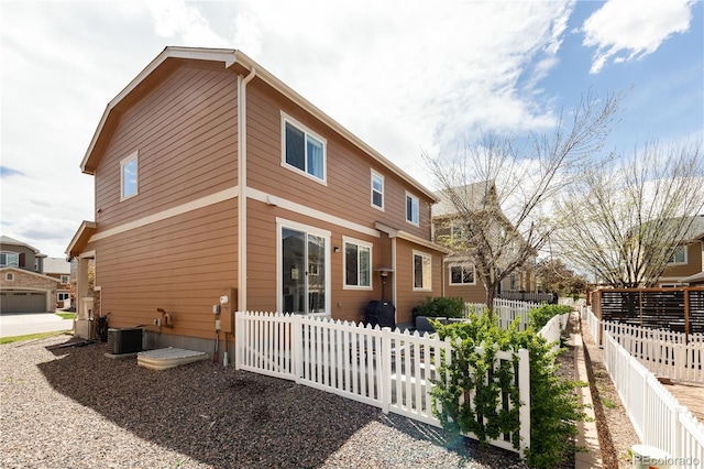 rear view of property featuring fence and central AC