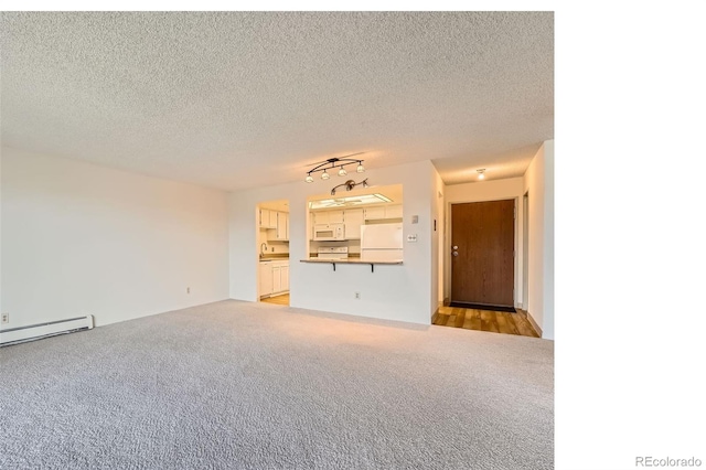 unfurnished living room featuring light colored carpet, baseboard heating, a sink, and a textured ceiling