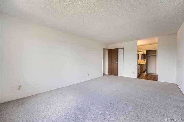 unfurnished room with dark carpet and a textured ceiling