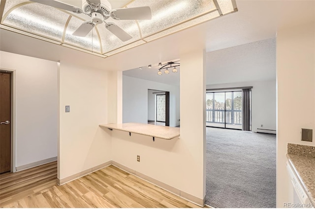 empty room with a ceiling fan, a baseboard radiator, light wood-style floors, and baseboards