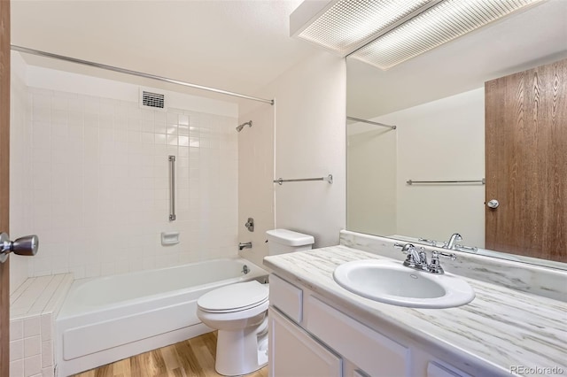 bathroom with wood finished floors, toilet, vanity, and bathing tub / shower combination