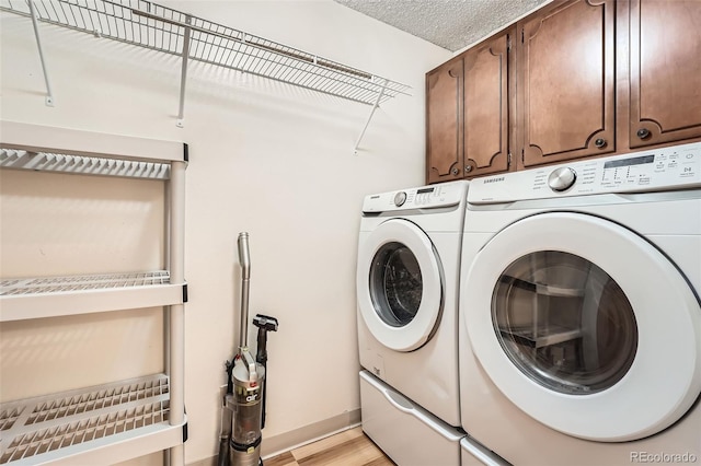 clothes washing area featuring washer and dryer, cabinet space, light wood-style flooring, baseboards, and a textured ceiling