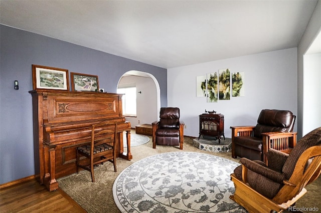 3530 Doolittle Rd, Monument, CO 80132 - living area featuring arched walkways, wood finished floors, a wood stove, and baseboards
