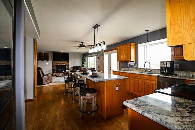 3530 Doolittle Rd, Monument, CO 80132 - kitchen with a sink, a center island, ceiling fan, dark wood-style floors, and a stone fireplace