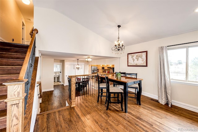 dining area with wood-type flooring, vaulted ceiling, and a notable chandelier