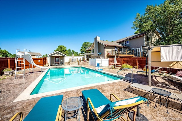 view of swimming pool featuring a patio, a water slide, and a shed