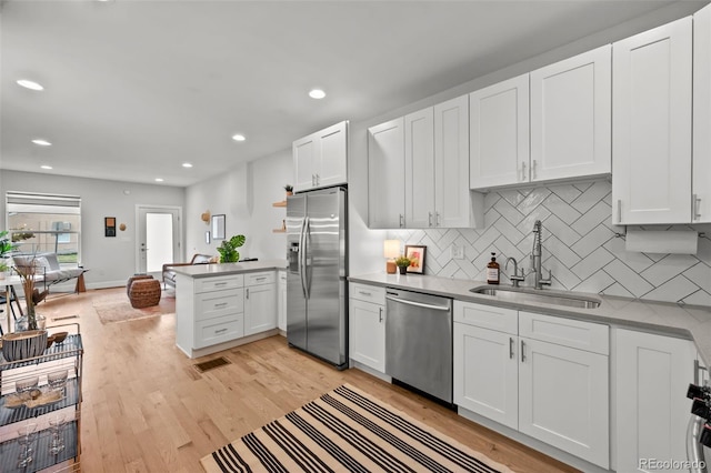 3003 California St, Denver, CO 80205 - kitchen with stainless steel appliances, a peninsula, white cabinets, backsplash, and light wood finished floors