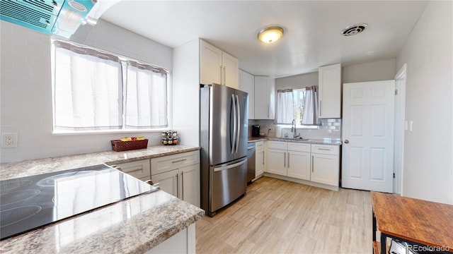 kitchen with sink, stainless steel appliances, light wood-type flooring, and white cabinetry