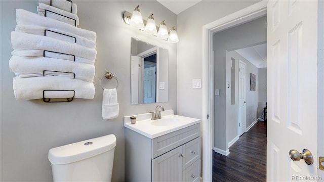 bathroom with wood-type flooring, vanity, and toilet