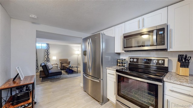 kitchen featuring light hardwood / wood-style floors, stainless steel appliances, white cabinetry, and a textured ceiling