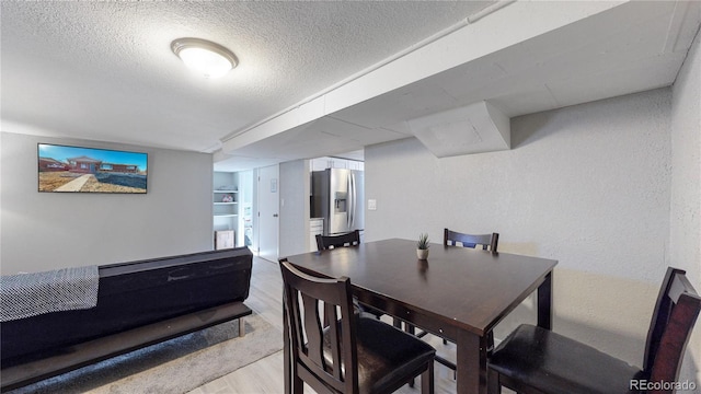 dining area featuring light hardwood / wood-style flooring and a textured ceiling