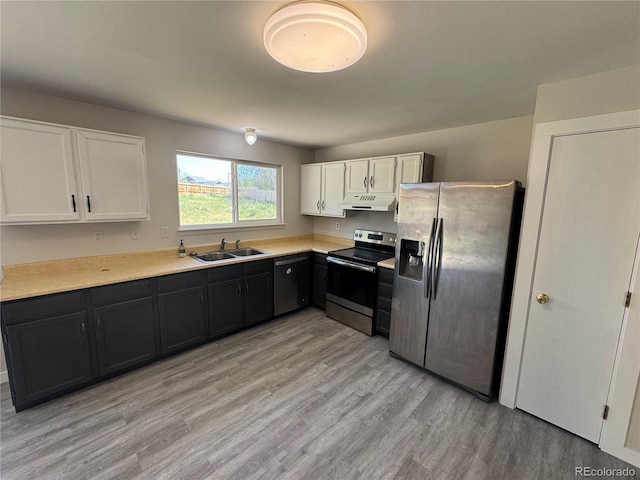 kitchen with stainless steel appliances, a sink, under cabinet range hood, white cabinetry, and light wood-style flooring