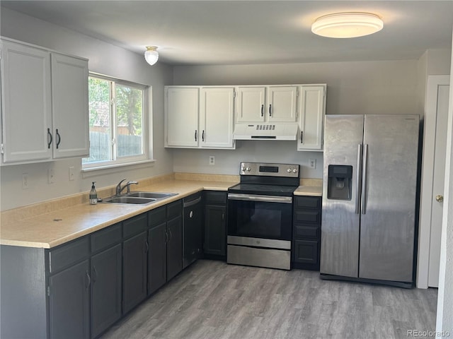 kitchen with appliances with stainless steel finishes, under cabinet range hood, a sink, white cabinets, and light countertops