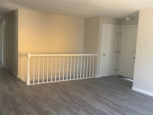 empty room featuring dark wood-style flooring, baseboards, and a textured ceiling
