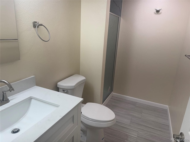 full bathroom featuring a stall shower, toilet, and vanity
