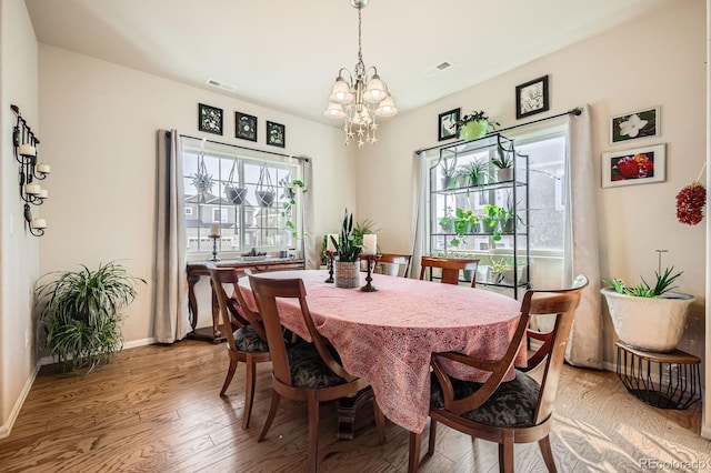 dining space featuring visible vents, baseboards, a notable chandelier, and wood finished floors