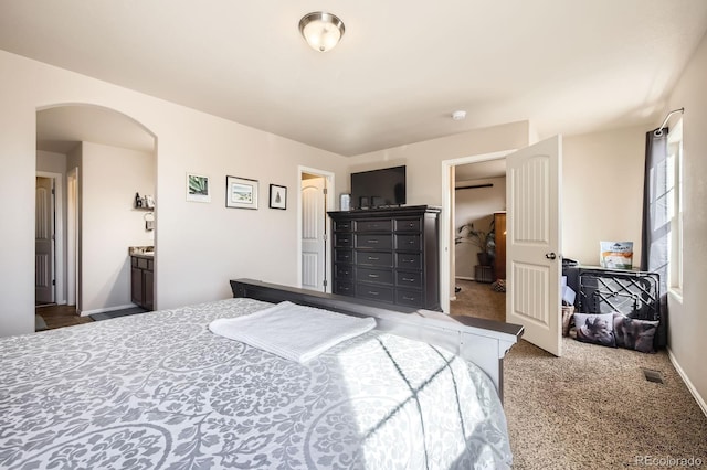 bedroom with carpet, arched walkways, and baseboards