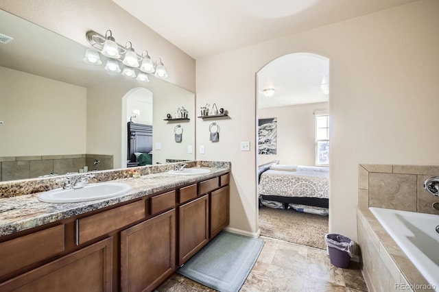 ensuite bathroom featuring a sink, double vanity, a bath, and ensuite bathroom