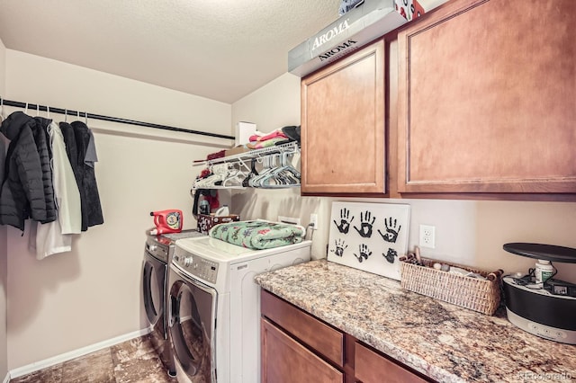 laundry area with washing machine and clothes dryer, cabinet space, a textured ceiling, and baseboards