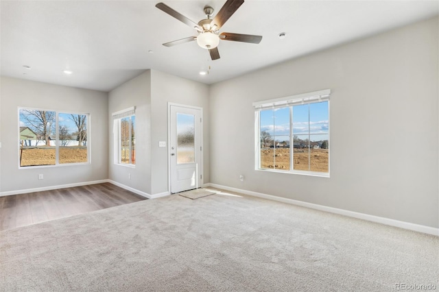 empty room featuring a wealth of natural light, ceiling fan, and light colored carpet