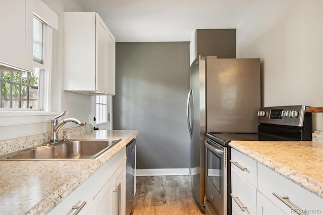 kitchen featuring stainless steel appliances, white cabinetry, light hardwood / wood-style floors, and sink