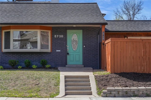 5730 E 19th Ave, Denver, CO 80220 - view of exterior entry with a shingled roof, brick siding, and fence
