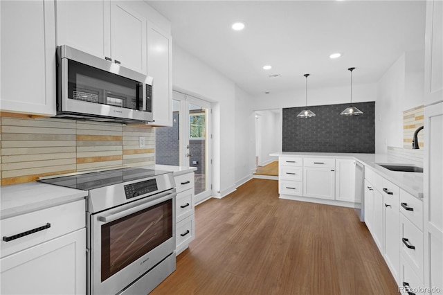5730 E 19th Ave, Denver, CO 80220 - kitchen with appliances with stainless steel finishes, a sink, tasteful backsplash, a peninsula, and white cabinets