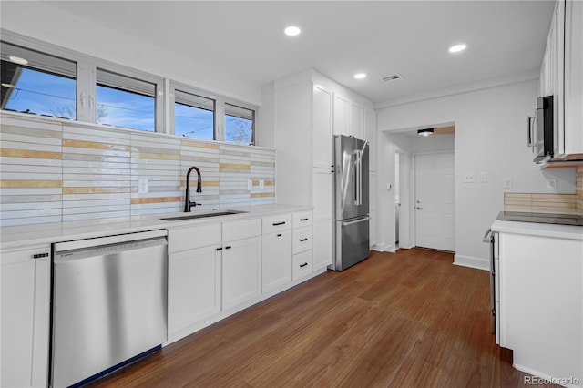5730 E 19th Ave, Denver, CO 80220 - kitchen with stainless steel appliances, a sink, decorative backsplash, dark wood-style flooring, and light countertops