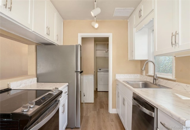 kitchen with light hardwood / wood-style floors, stainless steel appliances, sink, white cabinets, and washer / clothes dryer