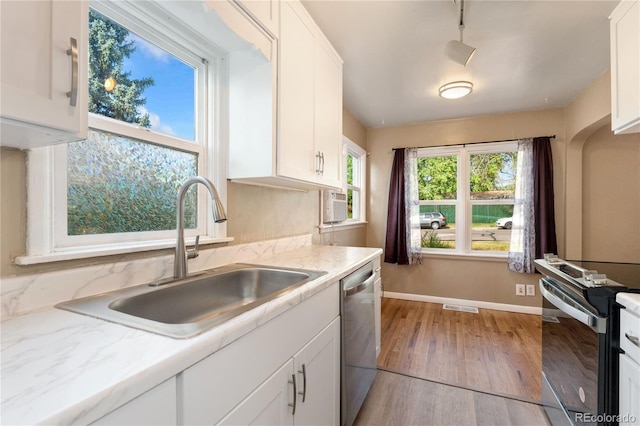 kitchen with white cabinets, stainless steel appliances, light hardwood / wood-style floors, and sink