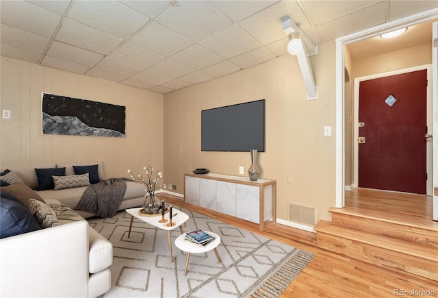 living room featuring a drop ceiling and wood-type flooring