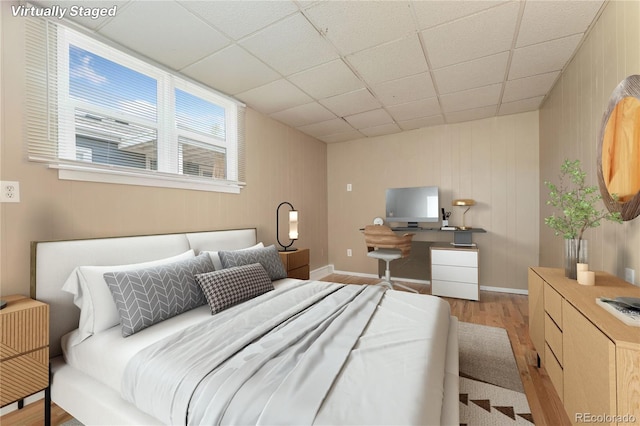 bedroom with light wood-type flooring and a drop ceiling