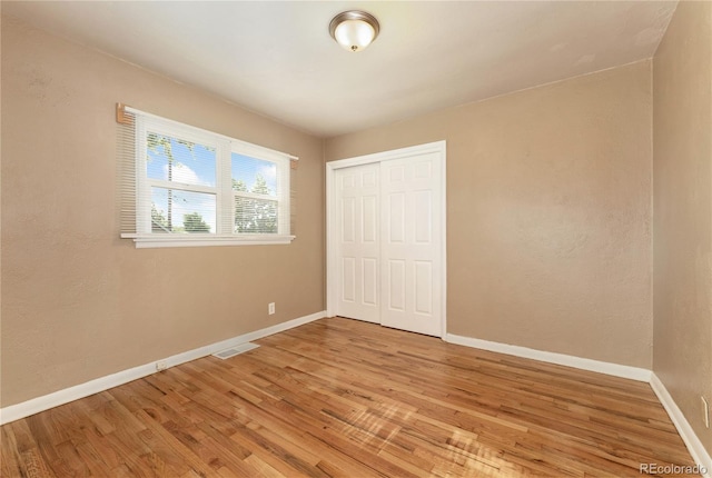 unfurnished bedroom featuring a closet and hardwood / wood-style flooring